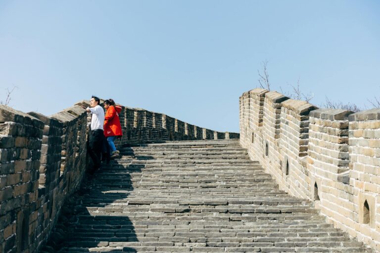 Tourists explore the historic Great Wall of China under clear blue skies, capturing its architectural beauty.