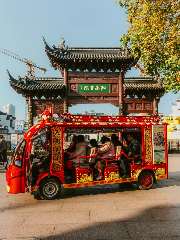 Vibrant street life at Nanjing Confucius Temple with tourists on a red shuttle.