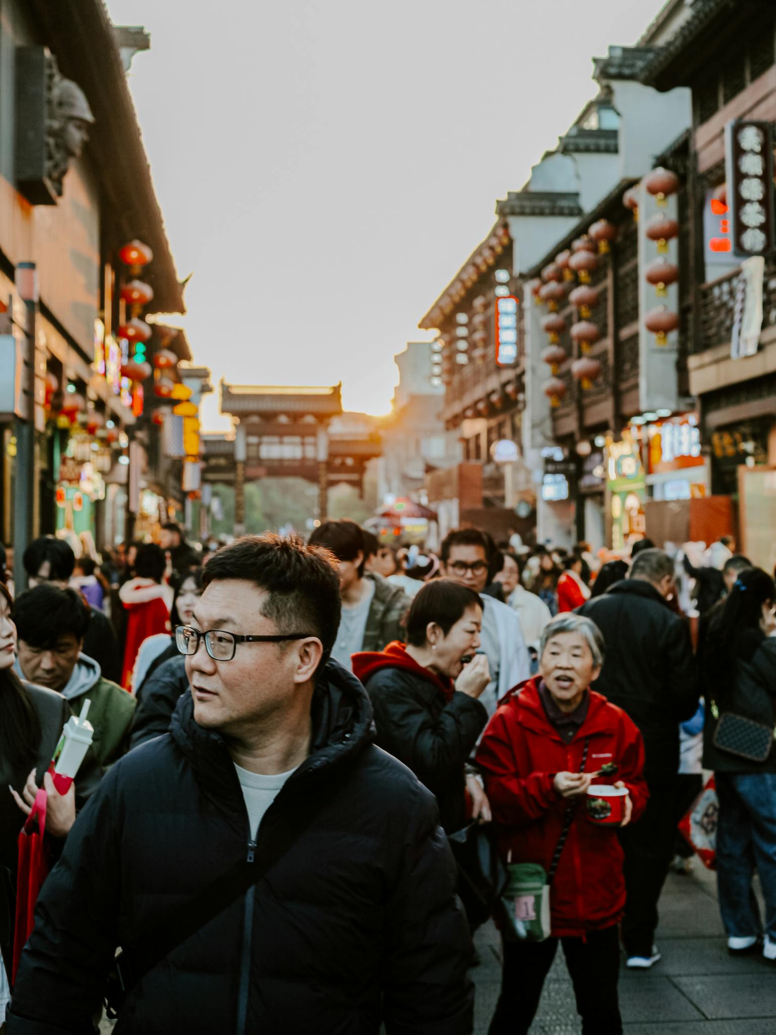 Vibrant street life in Nanjing with a diverse crowd and traditional architecture at sunset.